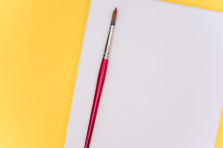 top view shot of blank white paint canvas and tools on a yellow paper surface with copy spaceの写真素材