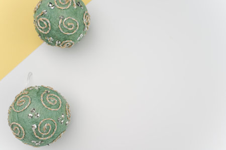 Green Christmas decorative balls with sapce for text on a white yellow paper surfaceの写真素材