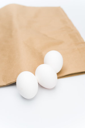 organic white eggs on a white and brown paper surface with copy space for textの写真素材