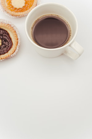 isolated apricot and cherry jam tart in a paper backing cup and cup of coffee on a white background with text spaceの写真素材
