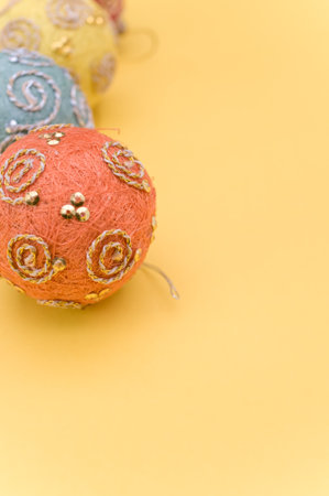 Multicolored Christmas decorative balls with sapce for text on a yellow surfaceの写真素材