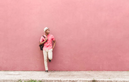 man with backpack and hat stand over a colorful wall on the street city urban concept.
