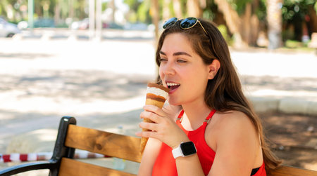 Woman side view eating one vanilla chocolate ice cream cone.