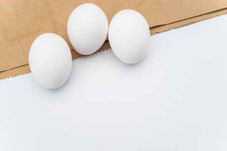 organic white eggs on a white and brown paper surface with copy space for textの写真素材