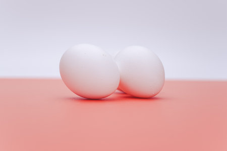 organic white eggs on a white salmon pink  surface with copy space for text