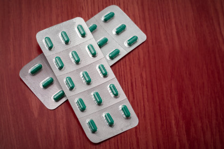 blisters with medicinal capsules on a reddish wood base