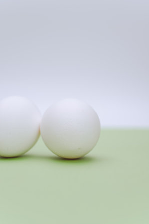 organic white eggs on a white and green surface with copy space for text