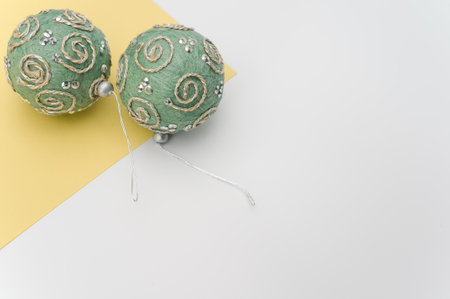 Green Christmas decorative balls with sapce for text on a white yellow paper surfaceの写真素材