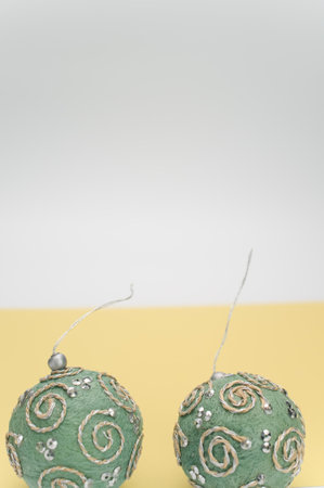 Green Christmas decorative balls with sapce for text on a white yellow paper surfaceの写真素材