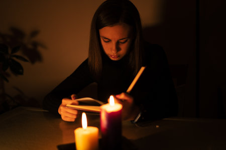 Young woman reading by candlelight. Blackout concept, power cutの写真素材