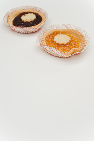 isolated apricot and cherry jam tart in a paper backing cup on a white background with text spaceの写真素材