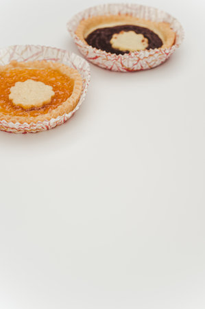 isolated apricot and cherry jam tart in a paper backing cup on a white background with text space