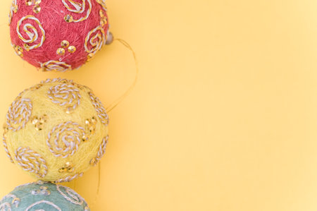 Multicolored Christmas decorative balls with sapce for text on a yellow surfaceの写真素材