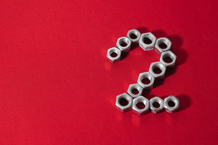 number two, made with steel nuts on red fabric background