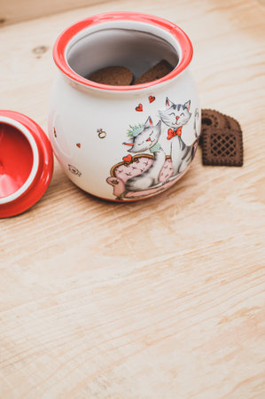 cocoa and chocolate cookies in a finely decorated stoneware jar on a rough wood tabletop with text spaceの写真素材