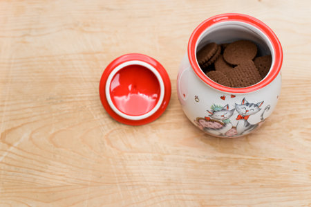 cocoa and chocolate cookies in a finely decorated stoneware jar on a rough wood tabletop with text spaceの写真素材