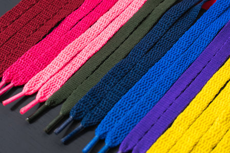 background of colored shoelaces on black wood, arranged diagonally, concept of perfection, leaving...