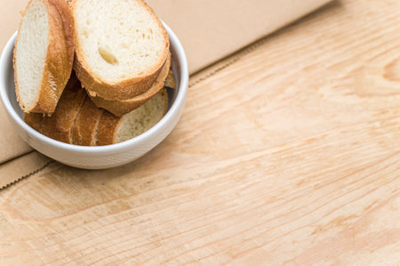 organic fresh sliced bread in a white bowl on a wooden tabletop with copy space
