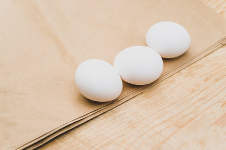 organic white eggs on a natural wooden and brown paper background with copy space for textの写真素材