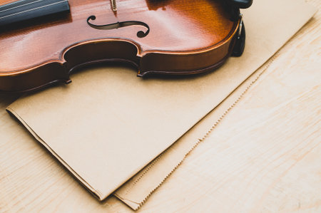 top view of elegant acoustic violin on a wooden tabletop and brown paper backgroundの写真素材
