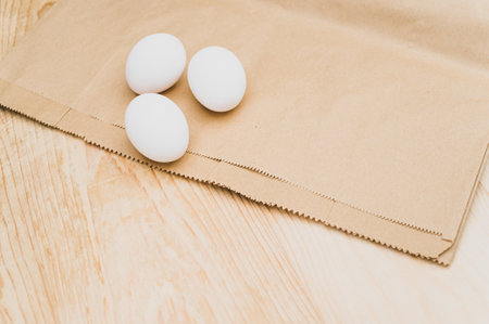 organic white eggs on a natural wooden and brown paper background with copy space for textの写真素材