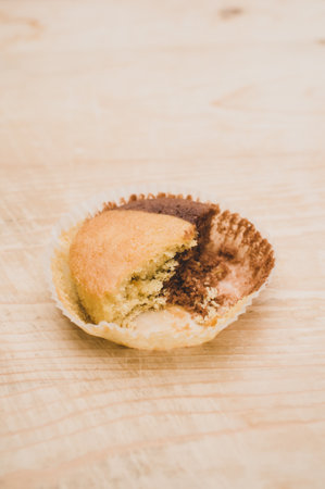 nibbled organic chocolate cupcake on a rough wooden background with text spaceの写真素材