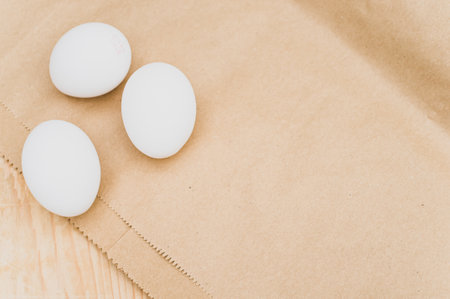 organic white eggs on a natural wooden and brown paper background with copy space for text