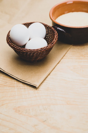 white eggs and terracotta bowl with wholegrain flour on rustic wooden background with copy spaceの写真素材