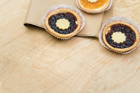 isolated apricot and cherry jam tart on a wood and brown paper tabletop background with text spaceの写真素材