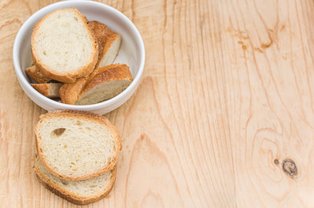 organic fresh sliced bread in a white bowl on a wooden tabletop with copy spaceの写真素材