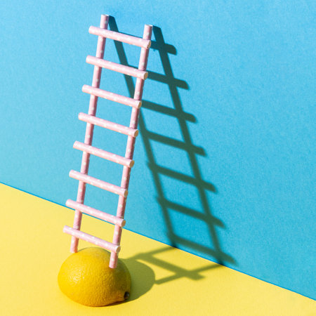 Ladder on lemon, with sunshine shadow against yellow and blue pastel background.Creative minimal composition.の写真素材