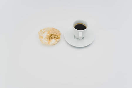 black hot ristretto coffe in a white stoneware cup with plate with nibbled pie on a white surface with text spaceの写真素材