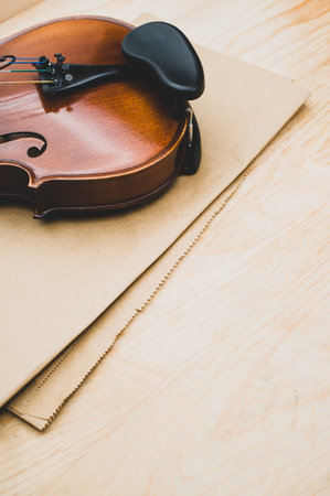 top view of elegant acoustic violin on a wooden tabletop and brown paper backgroundの写真素材