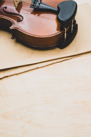 top view of elegant acoustic violin on a wooden tabletop and brown paper backgroundの写真素材