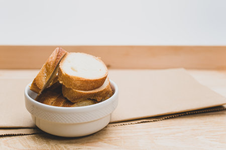 organic fresh sliced bread in a white bowl on a wooden tabletop with copy spaceの写真素材
