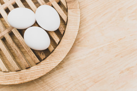 organic white eggs on a natural wooden tabletop surface with copy space for textの写真素材