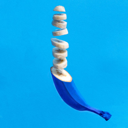 Sliced floating banana against blue background. Minimal natural concept.の写真素材
