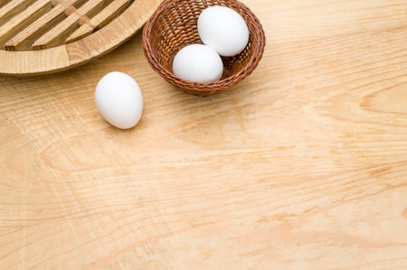 organic white eggs in a canister on a natural wooden tabletop surface with copy space for text