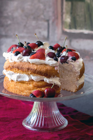 beautiful angel food cake covered in whipped cream and fresh colorful berriesの写真素材