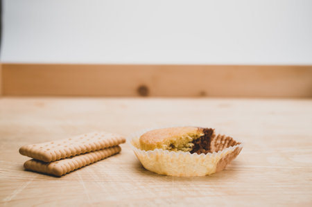 nibbled organic chocolate cupcake and biscuits on a rough wooden background with text space