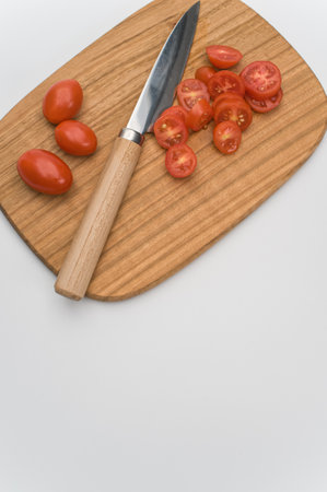 datterini tomatoes with chopping board and knife on a white surface with text spaceの写真素材