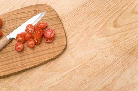 datterini tomatoes with chopping board and knife on a wooden surface with text space