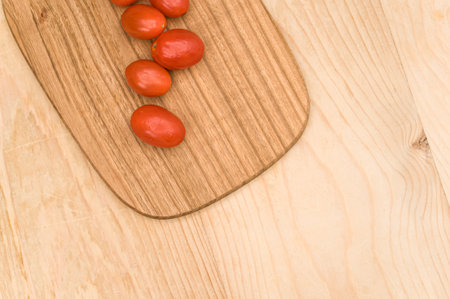 datterini tomatoes with chopping board on a wooden surface with text spaceの写真素材