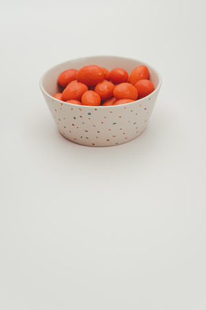 white decorated stoneware bowl full of datterini tomatoes on a white surface with text spaceの写真素材