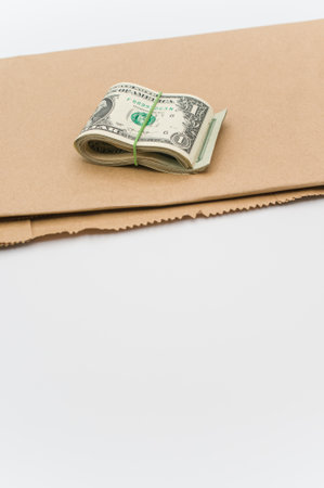 US dollar banknotes wad and brown paper on a white tabletop with text space