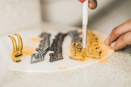 Close up view of a chef using a brush to decorate some elements to garnish of a cake in a kitchen