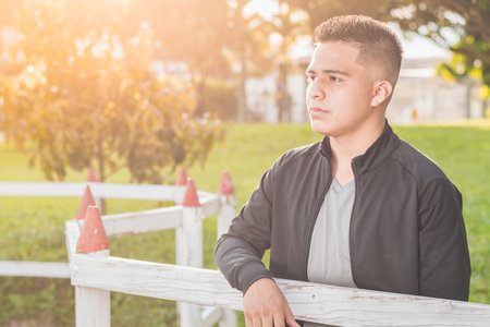 young male student by the wooden fence thinking about his future and thinking about his business, entrepreneur happy for his achievements, with beautiful sunset in the background.の写真素材