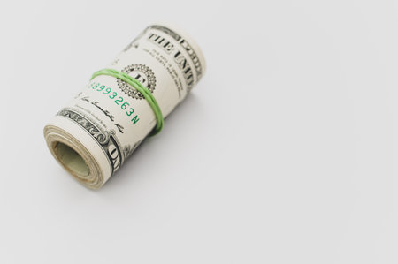US dollar banknotes rolled up on a white tabletop with text spaceの写真素材