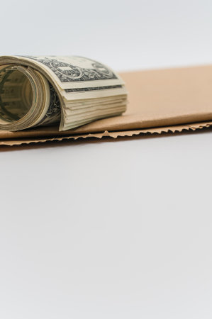rolled up US dollar banknotes and brown paper on a white tabletop with text spaceの写真素材