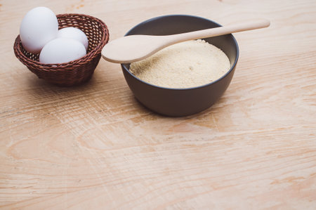 white eggs and dark gray bowl with wholegrain flour on worn wooden background with copy spaceの写真素材
